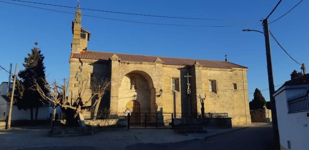Plano general con la iglesia parroquial de San Vicente Mártir en el municipio de Muga de Sayago, Zamora. La iglesia cuenta con un acceso porticado y un gran arco de medio punto. En su interior, varias tallas del 1600 y pinturas murales realizadas por el pintor zamorano Antonio Pedrero durante la segunda mitad del siglo XX